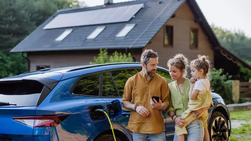Familie vor ladendem E-Auto