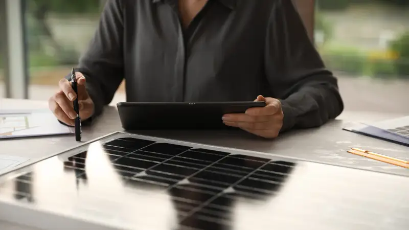 Frau mit Tablet vor Solarpanel