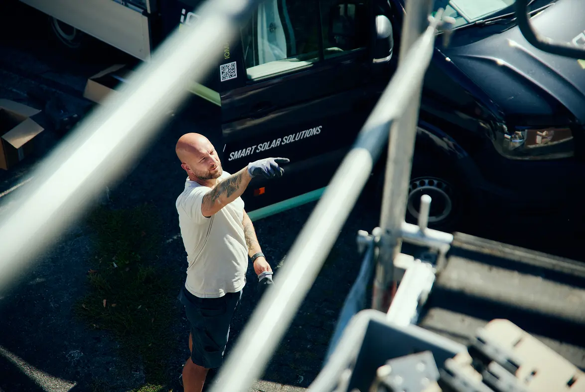 Monteur gibt vor einem iQma energy Firmenwagen Anweisungen